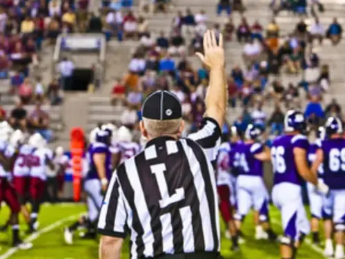 A referee holds his hand up at the line of scrimmage during a Holy Cross football game.