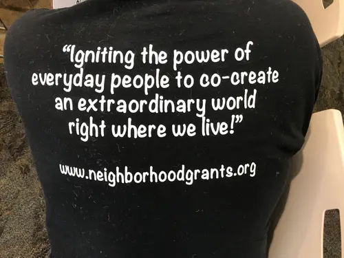 a shirt reads igniting the power of everyday people to co-create an extraordinary world right where we live!