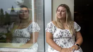 Woman sits on windowsill and looks out window