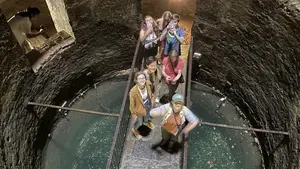 People stand on a bridge extending across the bottom of a giant well.