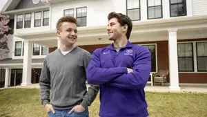 Two male college students standing outside their dorm.