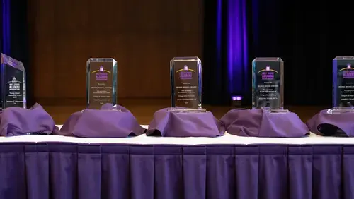 5 glass awards lined up on a table
