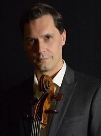 Man holding a cello, with a serious expression, dark background