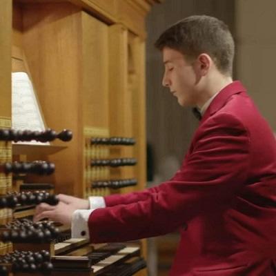 A photo of Matthew Luca, organ scholar, dressed in a red sport coat, playing the Taylor & Boody organ in St. Joseph Chapel, Holy Cross