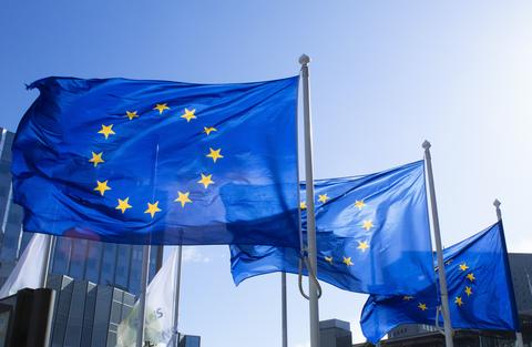 Three European Union flags flying outside building