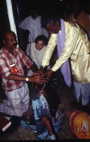 Man with hands over person in prayer