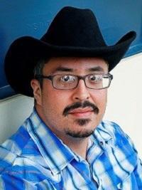 man with black cowboy hat, glasses and checkered shirt blue and white