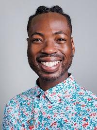close up image of a young man smiling at the camera wearing a bright patterned shirt