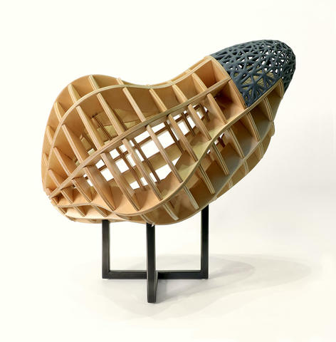 An abstract organic sculpture constructed of wood with various compartments, a section of gray 3D printed patterns at the top, sitting on a black stand.