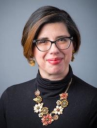 Photo of Dr. Imeratori-Lee the speaker for this event. She has short brown hair with reddish highlights, glasses and a black turtleneck with a statement necklace.