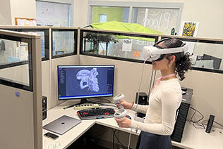 Student with VR headseat facing left against screen
