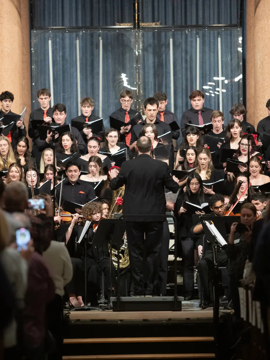 A conductor leads the orchestra at the 2025 Lessons and Carols  