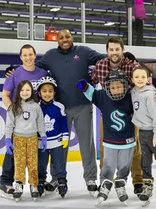 a group of adults and kids smiling while ice skating