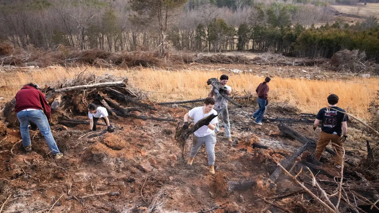 Group of students moving logs and branches