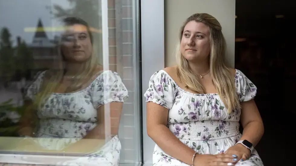 Woman sits on windowsill and looks out window