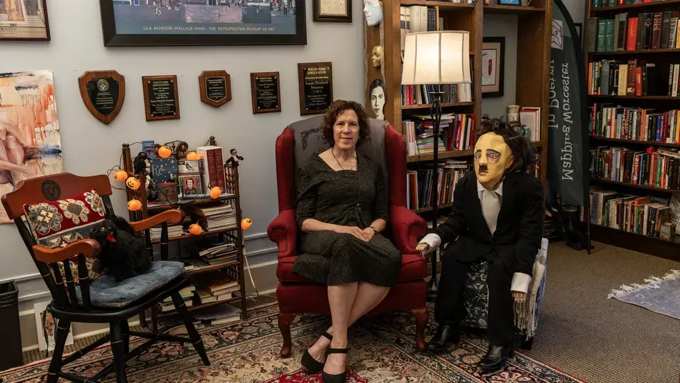 Woman, seated, with Edgar Allan Poe doll