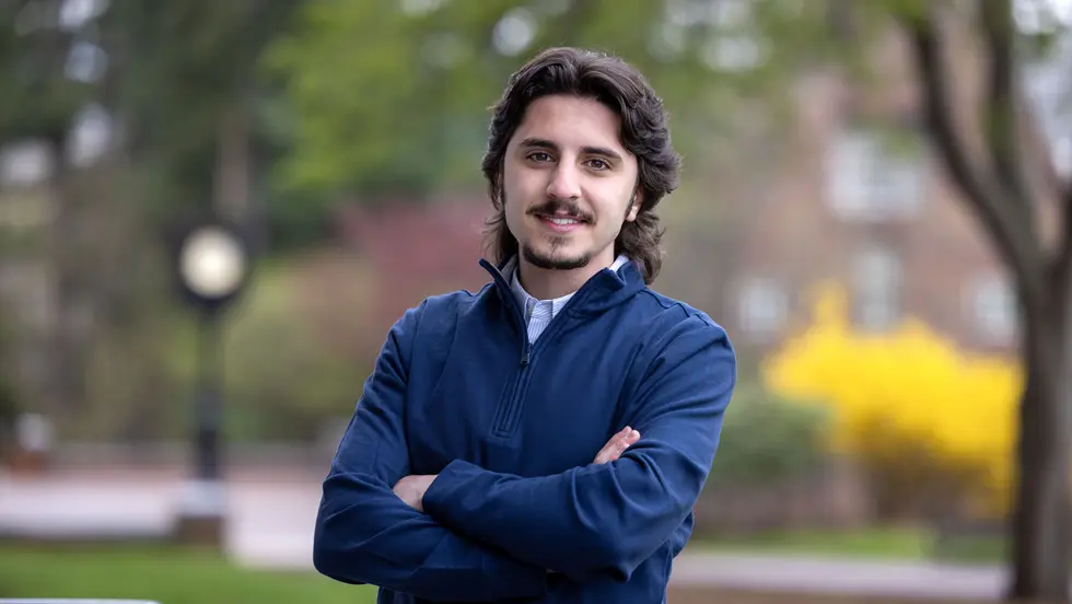 Man with beard stands with arms crossed