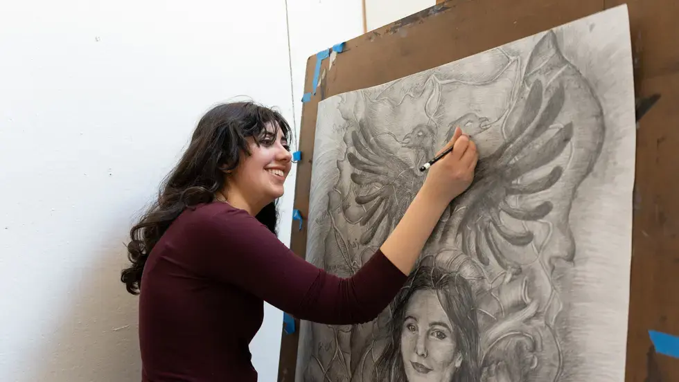 Sophie Sundaram working on a black and white drawing at an easel