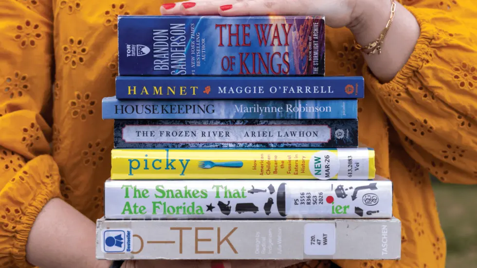 Hands holding a stack of books