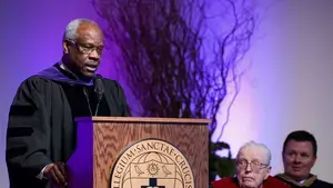 Clarence Thomas wearing commencement regalia and standing at a podium
