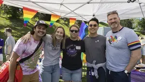 six individuals at at tailgate with rainbow flags behind them