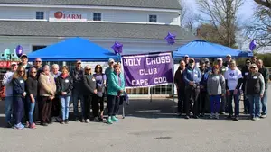 group of holy cross alumni holding a purple banner