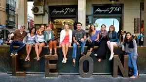 Group of students studying abroad in Spain and sitting on top of "Leon" sign or sculpture.