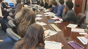 Business students sitting around brown table in an office.
