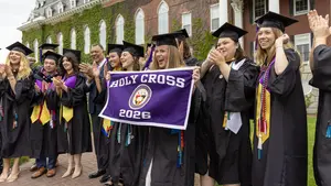 Graduates pose for a photograph with College President Vincent Rougeau in front of Fenwick Hall